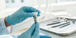A dental professional holds a dental implant, a skill learned in 2025 dental implant courses.